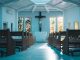 Bancs d’église en bois brun foncé à l’avant-plan. Au fond, crucifix au centre et deux vitraux de chaque côté. Murs, plafond et plancher de couleur bleu ciel.