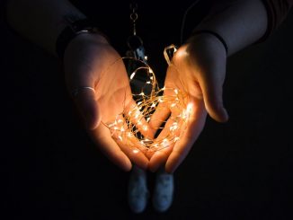 Guirlande lumineuse dans les mains d’une personne à l’avant-plan. Arrière-plan dans le noir.