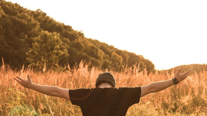 Homme en prière au milieu d’un champ durant le jour.