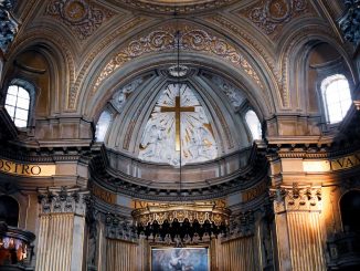 Gros plan de l’intérieur d’une cathédrale. On voit la partie haute du chœur et la croix centrale.