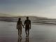 Homme et femme se tenant la main en marchant sur un plan d’eau.