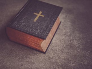 Bible fermée avec couverture noire sur une surface grise.