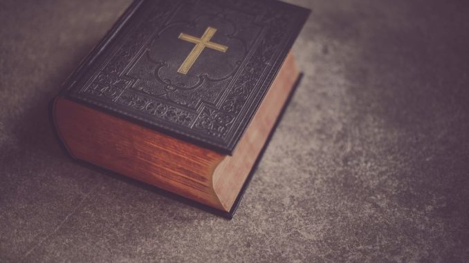 Bible fermée avec couverture noire sur une surface grise.