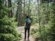 Homme portant un sac à dos bleu marchant dans la forêt.