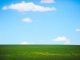 Photographie de paysage de champ vert et de ciel bleu.