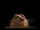 Homme en prière les mains jointes sur la Bible.