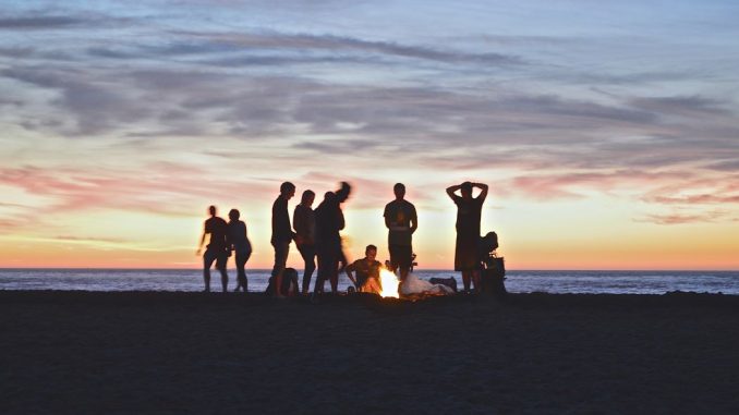 Groupe de personnes installant un feu de camp sur une plage.