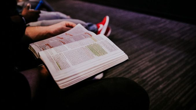 Personne lisant la bible. L’éclairage est centré sur la bible.