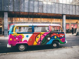 Mini-fourgonnette multicolore garée sur le bord de la route avec un signe de paix sur la porte.