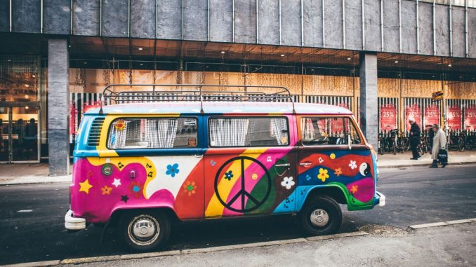 Mini-fourgonnette multicolore garée sur le bord de la route avec un signe de paix sur la porte.