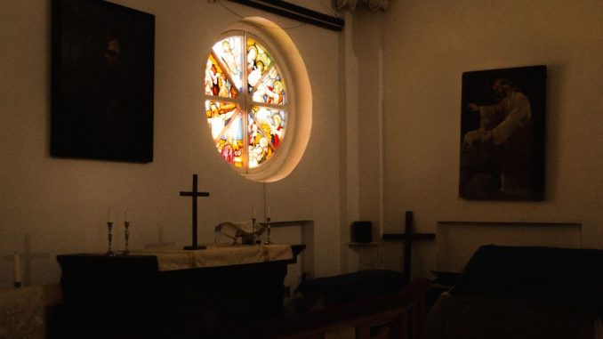 Croix noire sur un autel dans une petite chapelle.