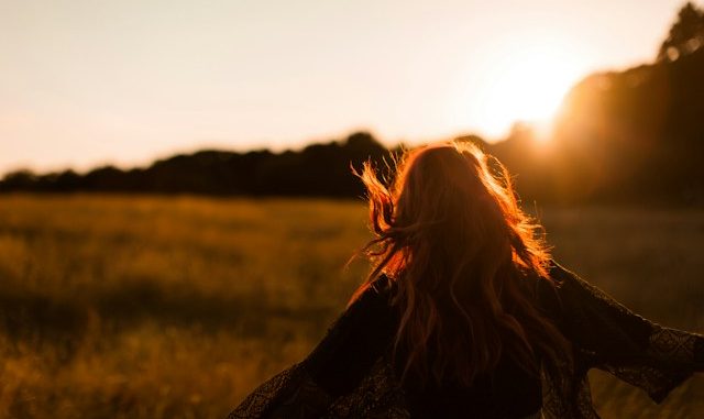 Femme debout dans un champ d’herbe. Image floue.