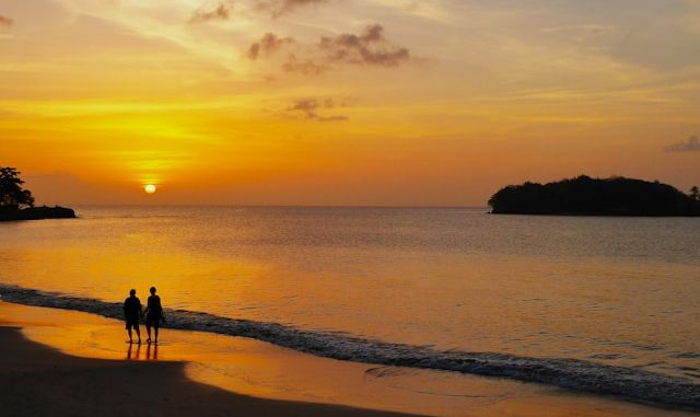 Deux personnes sur la plage au coucher du soleil.