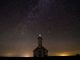 White chapel (call to holiness) under starry sky. Foreground in the dark and glow on the horizon in the background.