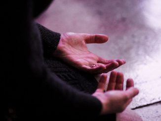 Person in black long sleeve shirt, seated and palms of hands facing upwards.