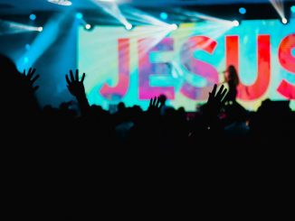 Silhouette of people raising hands during a performance to honour Jesus.