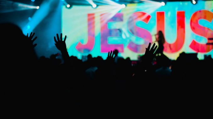 Silhouette of people raising hands during a performance to honour Jesus.