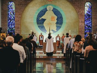Several priests and many people gathered in a small church.