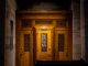 Confessional with three doors in brown wood between two concrete walls.