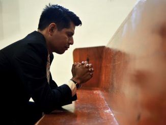 Man sitting, closing his eyes and praying.