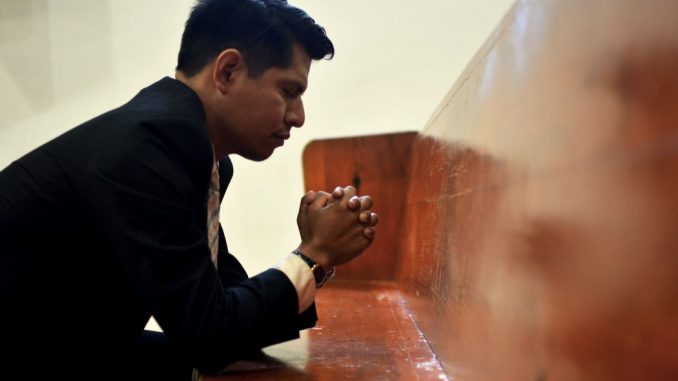 Man sitting, closing his eyes and praying.