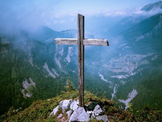 Brown wooden cross at cliff during daytime.
