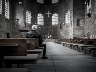 Person sitting on pew inside church.