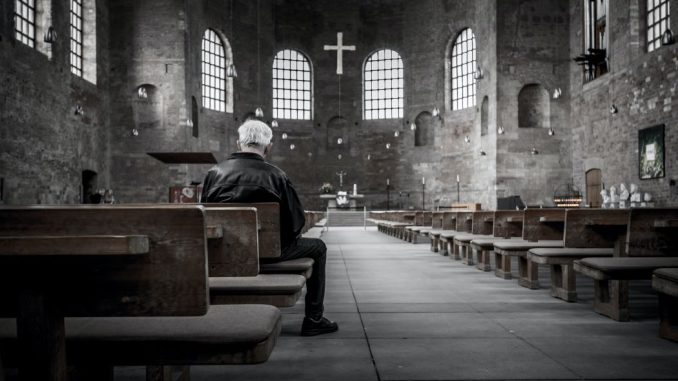 Person sitting on pew inside church.