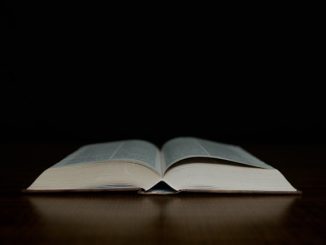 An open bible sitting on top of a wooden table.