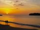 Two persons on beach during sunset.
